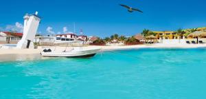 a boat in the water next to a beach at Hermosa Casa Vacacional Puerto Morelos in Puerto Morelos