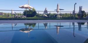 a pool of water with tables and umbrellas and chairs at SPA Roero Relax Resort in Canale