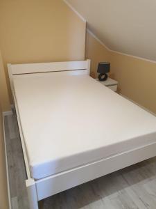Una cama blanca en una habitación pequeña con en Arielle, en Łazy