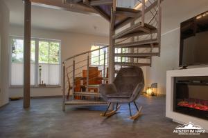 a living room with a chair and a spiral staircase at Ferienloft am Steinweg in Elbingerode