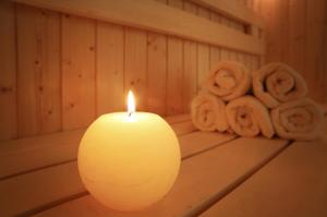 a candle on a table next to a pile of towels at Atrium Agárd Panzió in Gárdony