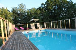 a swimming pool with two chairs and an umbrella at Gîte La grave haute sud in Mauzac-et-Grand-Castang