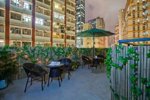 een patio met tafels en stoelen en een parasol bij Mingle by The Park in Hong Kong