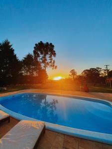 a large swimming pool with a sunset in the background at Pousada La Vista in Gramado