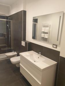 Un baño con lavabo, inodoro y espejo. en Roma Ariston 7, en Bolzano 7 fotos más