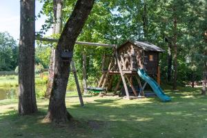 un parque infantil con un tobogán y un árbol en Namelis prie Širvintos upės su pirtimi, en Širvintos