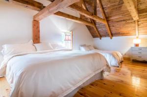 Cottage Jacques Cartier في ستونهارم: غرفة نوم بسرير ابيض كبير وسقف خشبي
