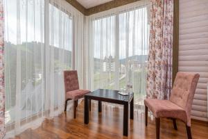 a table and two chairs in a room with windows at Hotel Pid Strihoju in Bukovel
