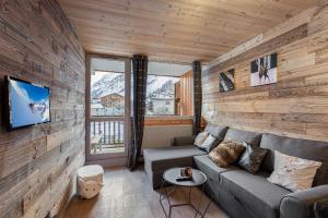 een woonkamer met een bank en een tv bij Appartement de charme hyper centre à Val d'Isère in Val dʼIsère