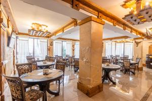 a restaurant with tables and chairs and windows at Hotel Pid Strihoju in Bukovel