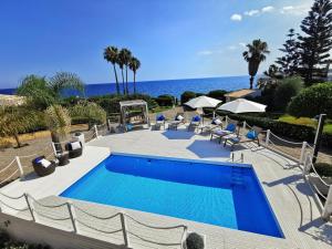 a swimming pool with chairs and the ocean in the background at Villa Arenile - Seaside - Swimmingpool- Private access to Sea - waterfront - Fontane Bianche - Siracusa in Fontane Bianche