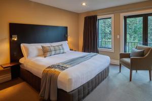 a hotel room with a large bed and a chair at Platinum Queenstown in Queenstown