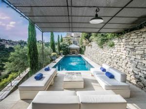 a swimming pool with white furniture and a stone wall at Villa Sunset in Gordes in Gordes +14 photos