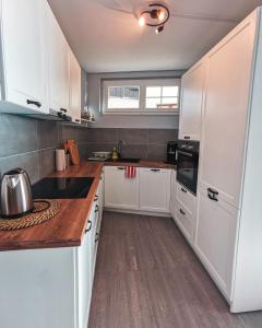 a kitchen with white cabinets and a wooden counter top at Solarberg Apartment in Andermatt