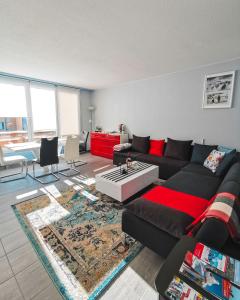 sala de estar con sofá negro y alfombra en Solarberg Apartment, en Andermatt