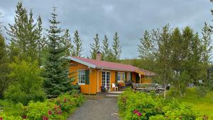 une petite maison orange dans un jardin fleuri dans l'établissement Hagi 2 Holiday Home, à Hagi