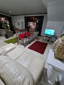 uma sala de estar com um sofá branco e uma televisão em VITORIA GARDEN em Águas de Lindoia
