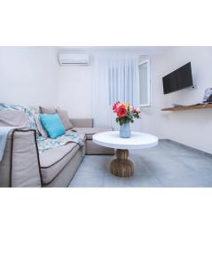 メソギーにあるAthena Luxury Apartmentsのリビングルーム(ソファ、花のテーブル付)