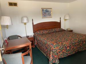 a bedroom with a bed and a desk and a chair at Budget Lodge Inn - Abilene in Abilene