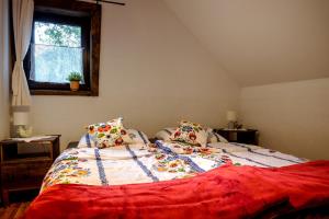 a bedroom with a bed with a red blanket and a window at Wiejski Dworek in Solina