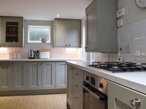 a kitchen with white cabinets and a stove top oven at Lovely old cottage in Stratford-upon-Avon