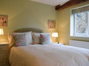 Un dormitorio con una cama blanca con almohadas y una ventana en Lovely old cottage, en Stratford-upon-Avon