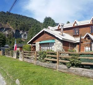 a wooden house with a fence in front of it at Hosteria Rayen in La Junta
