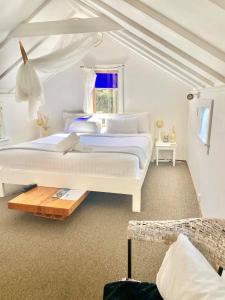 a white bedroom with a large bed and a window at Waiheke Island Guesthouse in Ostend