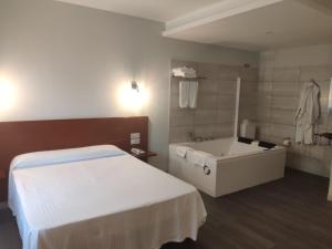 sypialnia z łóżkiem, wanną i umywalką w obiekcie Motel Caldas w mieście Caldas de Reis