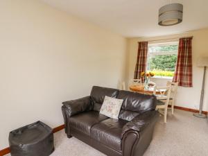 a living room with a leather couch and a table at Red Kite Cottage in Llandrindod Wells
