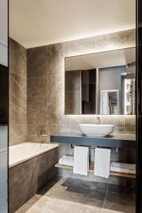 a bathroom with a sink and a tub and a mirror at Radisson Blu Hotel, Madrid Prado in Madrid