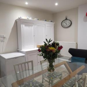 a dining room with a glass table with a vase of flowers at Frog Palace - Secure Parking-Outside Area-Topsham-Exeter-Beach-Chiefs-WiFi in Topsham