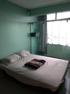 uma cama num quarto com uma janela em Apartamento NA PRAIA, 2 suites com cozinha em Ilhéus