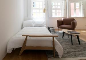 een slaapkamer met een bed, een stoel en een tafel bij Souto Apartments in Porto