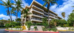 a building with palm trees in front of a street at Castle at Maui Banyan in Wailea