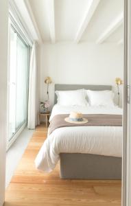 a white bedroom with a bed with a hat on it at Souto Apartments in Porto