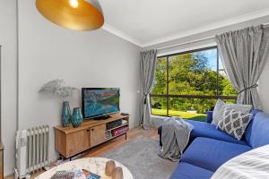 ein Wohnzimmer mit einem blauen Sofa und einem TV in der Unterkunft Lilyview Cottage - Robertson in Robertson