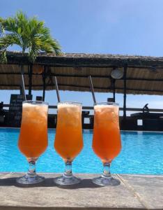 a group of three drinks sitting on a table next to a pool at Mui Ne Hills Budget Hotel in Mui Ne