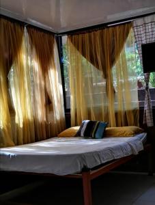 Cama en habitación con cortinas amarillas en Villa De Los Monos en Matapalo