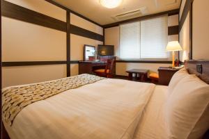 a hotel room with a large bed and a desk at Wasuki Tsukasakan in Kumamoto
