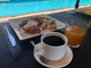 a cup of coffee and a plate of food and a glass of orange juice at Mui Ne Hills Villa Hotel in Mui Ne