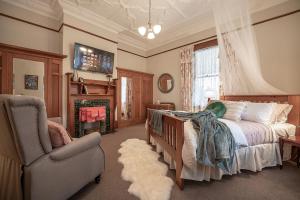 ein Schlafzimmer mit einem Bett, einem Stuhl und einem Kamin in der Unterkunft The Fern & Thistle Luxury Accommodation- Drinks, Hotpool, Sauna in Balclutha