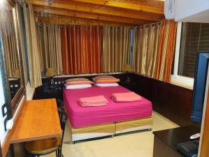 a small bedroom with a pink bed and a desk at Shefer Guesthouse in Eilat