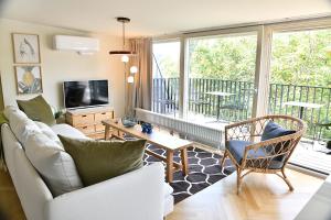 uma sala de estar com um sofá, uma televisão e uma varanda em JETHON Exklusives City-Appartement Bernburg em Bernburg