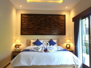 um quarto com uma cama branca e almofadas azuis em Cahaya Guest House em Ubud