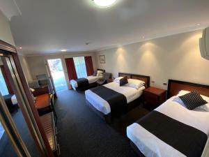 a hotel room with two beds and a living room at Best Western Plus All Settlers Motor Inn in Tamworth