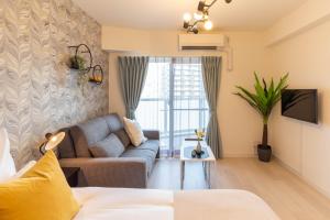 Bijou Suites Lieto APM في أوساكا: غرفة معيشة مع أريكة وتلفزيون