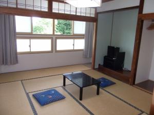 sala de estar con mesa de centro y TV en Pals Inn Raicho en Hakuba
