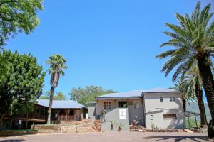 een huis met palmbomen ervoor bij Hardekool Guesthouse in Thabazimbi