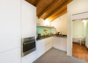 a kitchen with white cabinets and a wooden ceiling at BellaGiò Apartment pool free parking near lake in Bellagio